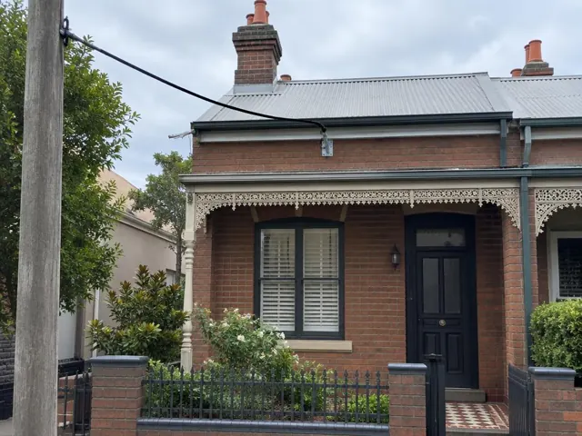 Overhead service cable and house bracket on a brick terrace facade in Summer Hill