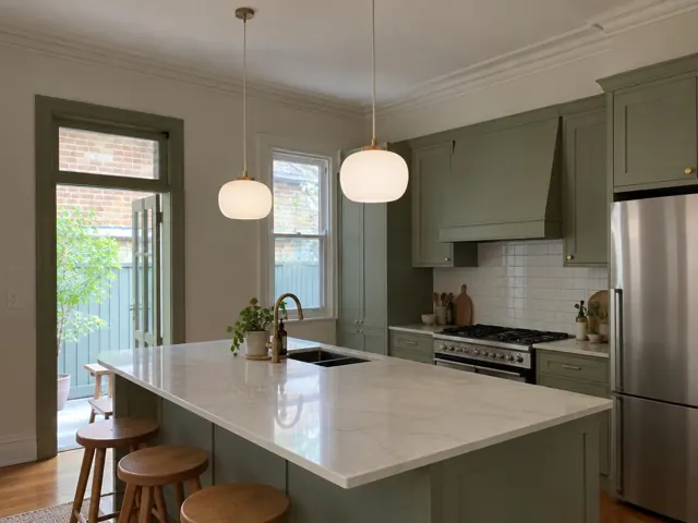 Two pendant lights over a kitchen island in a green-cabinet home with tiled splashback in Summer Hill